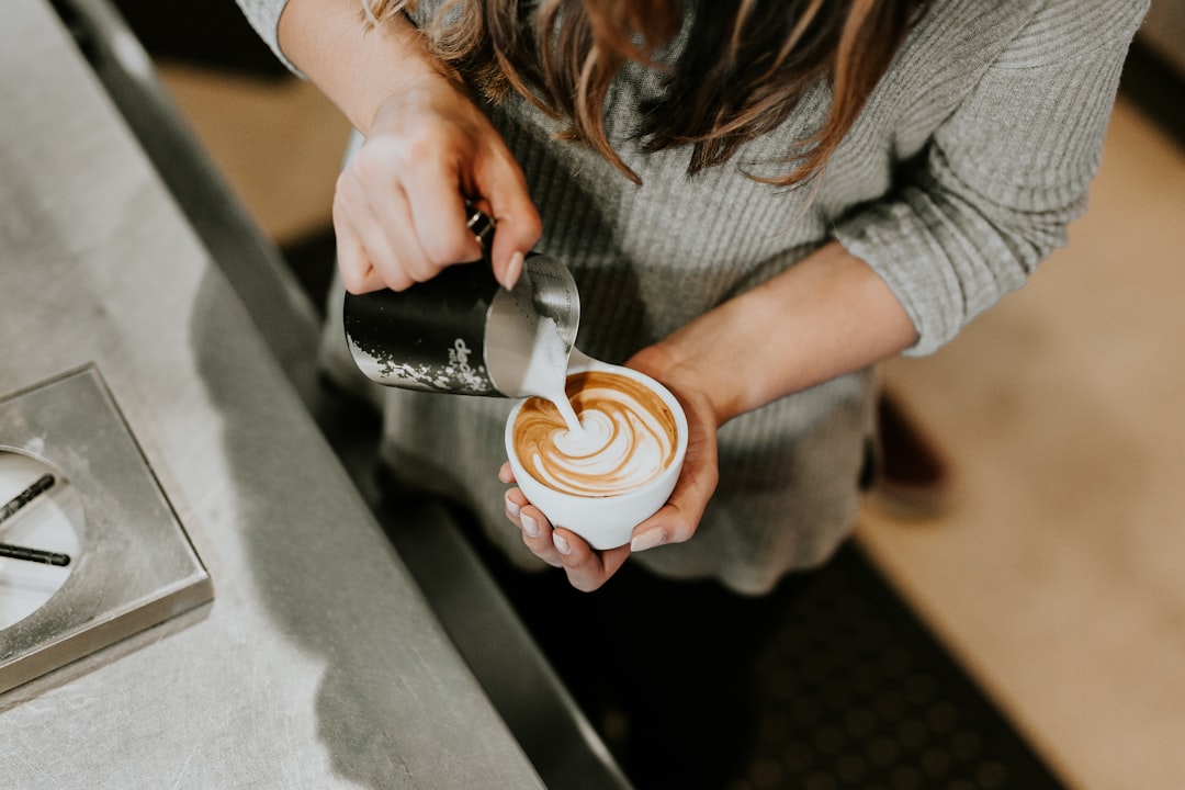 Barista pouring latte art into a ceramic cup