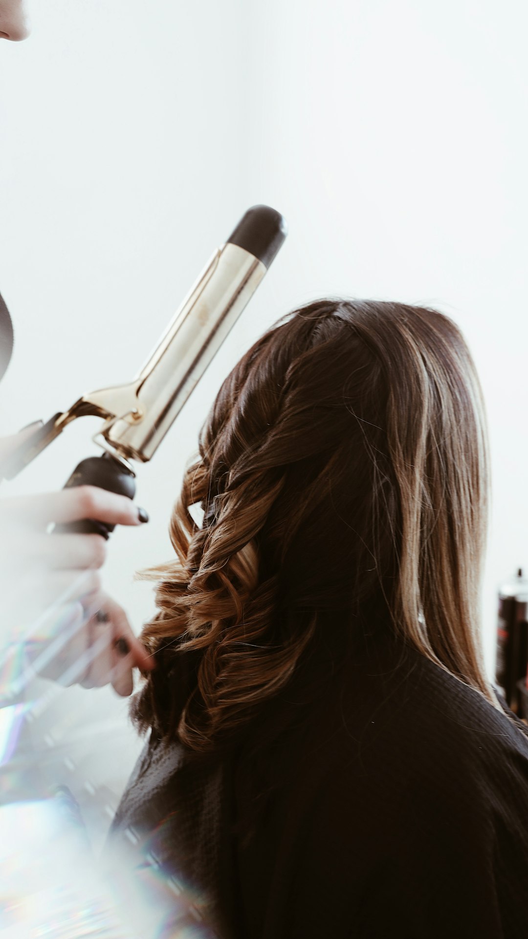 Stylist using a curling iron on long hair; stock inspiration